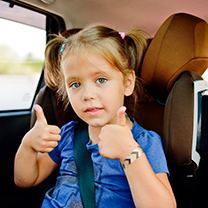 Kid in car seat hold two thumbs up